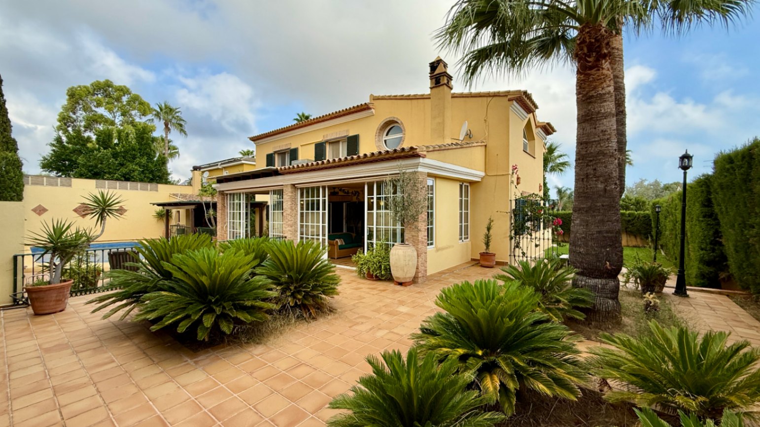 Ruim villa met zwembad, grote kelder en maximale privacy in Dénia Gelegen in een van de rustigste woonwijken van Dénia, combineert deze prachtige villa privacy, ruimte en een uitstekende verbinding met het stadscentrum. Gebouwd op een perceel van 811 m², omgeven door groen, biedt het een verzorgde en besloten omgeving, ideaal om te genieten van de rust zonder in te boeten op alle voorzieningen. De woning beschikt over vier slaapkamers, verdeeld over twee verdiepingen, en ruime, lichte ruimtes die zijn ontworpen voor dagelijks comfort. De keuken, van royale afmetingen, functioneert ook als eetkamer en ontvangt veel natuurlijk licht dankzij de grote ramen. Op de bovenverdieping bevindt zich een aparte kantoorruimte en de hoofdsuite, die beschikt over een eigen badkamer, inloopkast en balkon. Buiten steekt een mooie tuin met eigen bronirrigatie, een zwembad van 9 x 5 meter dat perfect in de omgeving is geïntegreerd, een zomerkeuken en een ruime glazen veranda met open haard, perfect om het hele jaar door van te genieten. De woning beschikt ook over een overdekte garage en ruime buitenruimtes. Een van de grootste aantrekkingskrachten van deze villa is de grote kelder die volledig is ingericht, droog en met uitstekende natuurlijke ventilatie, een zeer veelzijdige ruimte die momenteel een fitnessruimte, speelruimte en biljart bevat, en bovendien de mogelijkheid biedt om een sauna te installeren. De woning is uitgerust met airconditioning in de woonkamer en slaapkamers, een fotovoltaïsche installatie van meer dan 6 kW, alarmsysteem, veiligheidssloten, ramen met inbraakbescherming in verschillende ruimtes, horren, aparte wasruimte, osmosewater in de keuken, een olieopslag van 1.000 liter, aansluiting op het riolering en een compleet drainsysteem dat de kelder beschermt tegen vocht. Een eigendom van uitstekende constructkwaliteit, met ruime binnen- en buitenruimtes, ideaal als permanente woning of om het hele jaar van de Costa Blanca te genieten.