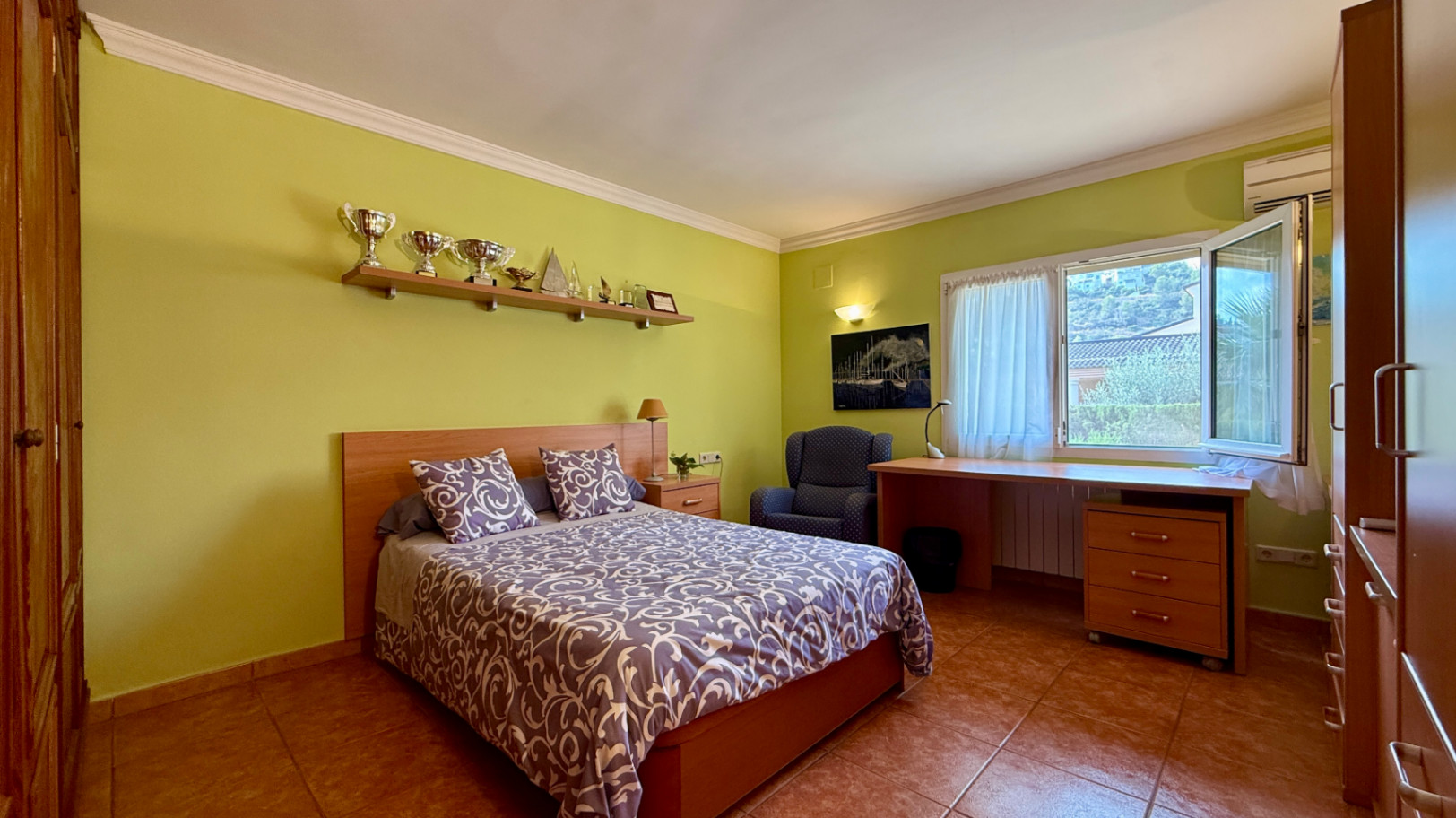 Ruim villa met zwembad, grote kelder en maximale privacy in Dénia Gelegen in een van de rustigste woonwijken van Dénia, combineert deze prachtige villa privacy, ruimte en een uitstekende verbinding met het stadscentrum. Gebouwd op een perceel van 811 m², omgeven door groen, biedt het een verzorgde en besloten omgeving, ideaal om te genieten van de rust zonder in te boeten op alle voorzieningen. De woning beschikt over vier slaapkamers, verdeeld over twee verdiepingen, en ruime, lichte ruimtes die zijn ontworpen voor dagelijks comfort. De keuken, van royale afmetingen, functioneert ook als eetkamer en ontvangt veel natuurlijk licht dankzij de grote ramen. Op de bovenverdieping bevindt zich een aparte kantoorruimte en de hoofdsuite, die beschikt over een eigen badkamer, inloopkast en balkon. Buiten steekt een mooie tuin met eigen bronirrigatie, een zwembad van 9 x 5 meter dat perfect in de omgeving is geïntegreerd, een zomerkeuken en een ruime glazen veranda met open haard, perfect om het hele jaar door van te genieten. De woning beschikt ook over een overdekte garage en ruime buitenruimtes. Een van de grootste aantrekkingskrachten van deze villa is de grote kelder die volledig is ingericht, droog en met uitstekende natuurlijke ventilatie, een zeer veelzijdige ruimte die momenteel een fitnessruimte, speelruimte en biljart bevat, en bovendien de mogelijkheid biedt om een sauna te installeren. De woning is uitgerust met airconditioning in de woonkamer en slaapkamers, een fotovoltaïsche installatie van meer dan 6 kW, alarmsysteem, veiligheidssloten, ramen met inbraakbescherming in verschillende ruimtes, horren, aparte wasruimte, osmosewater in de keuken, een olieopslag van 1.000 liter, aansluiting op het riolering en een compleet drainsysteem dat de kelder beschermt tegen vocht. Een eigendom van uitstekende constructkwaliteit, met ruime binnen- en buitenruimtes, ideaal als permanente woning of om het hele jaar van de Costa Blanca te genieten.